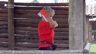 Com lenço no nariz por causa do cheiro, Andréa limpa chiqueiro